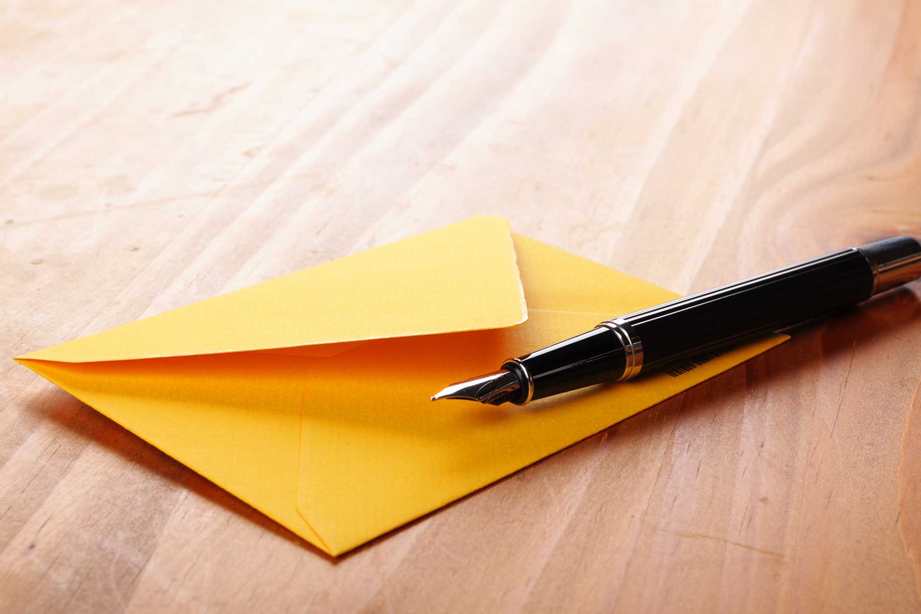 A picture of an open. envelope with a fountain pen, representing an open letter.